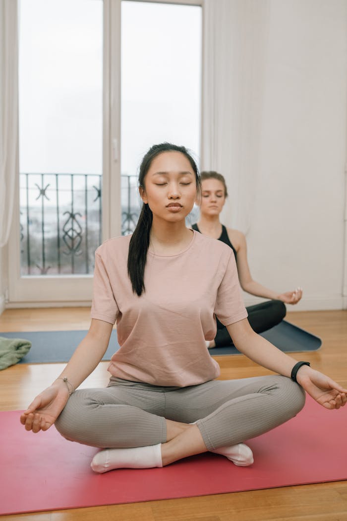 Services Two women practicing yoga meditation indoors for relaxation and mental health.